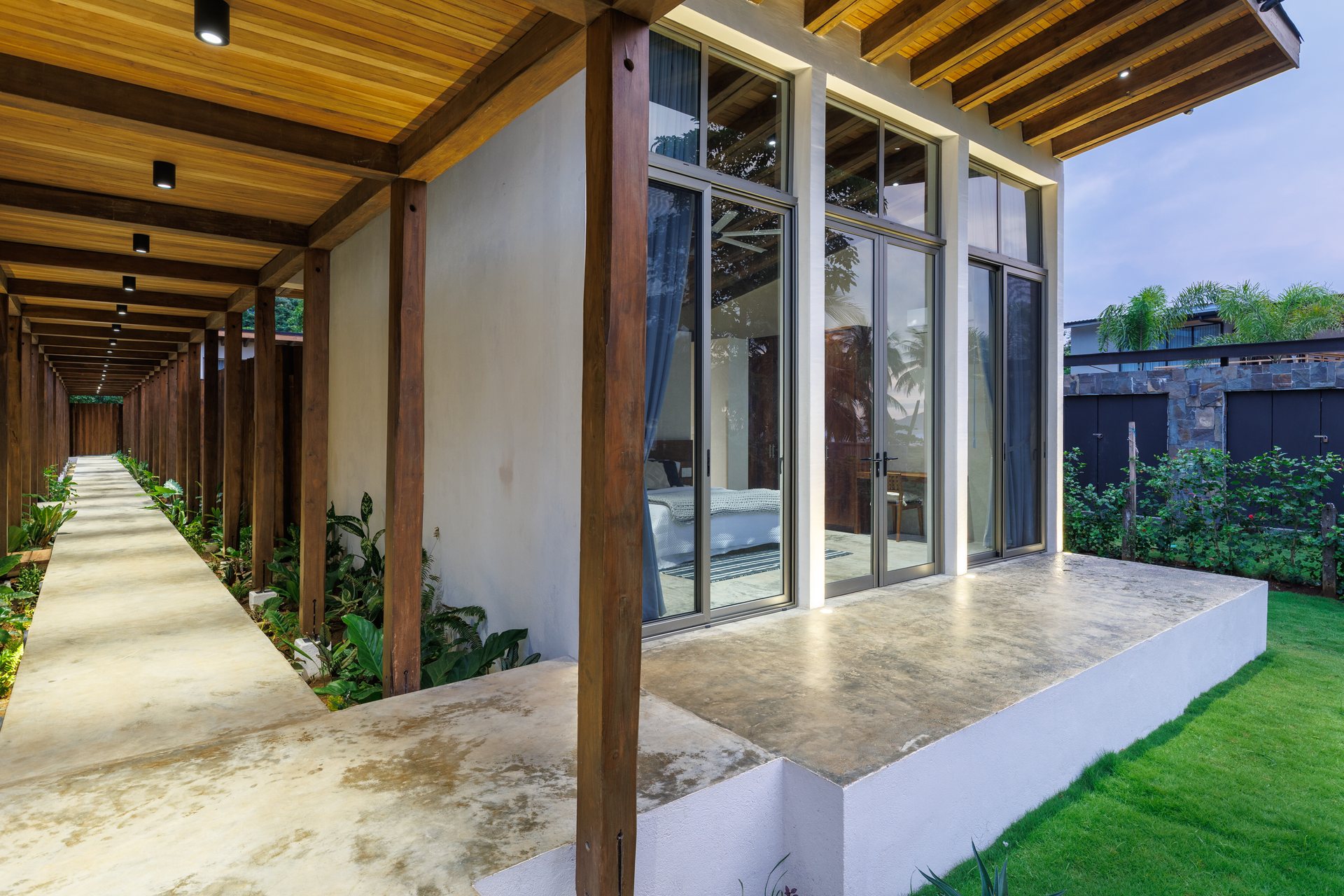 Long covered corridor with teak beams and slim columns, grand entrance at Mar del Sol Playa Coyote