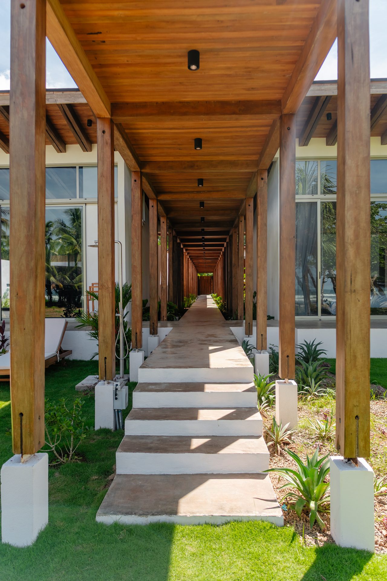 Approach walkway lined with palms, beachfront family villa