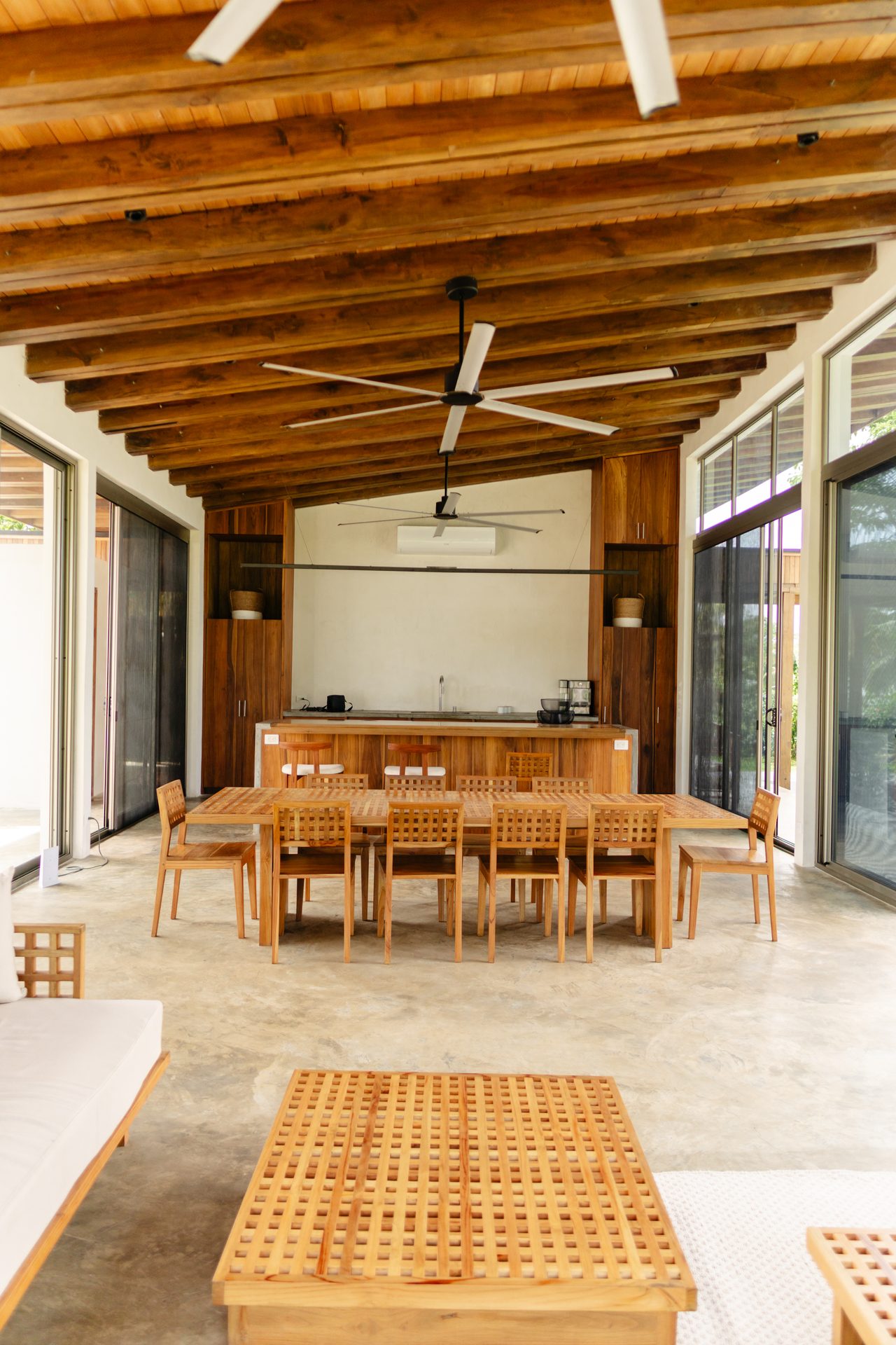 Open kitchen counter and dining table with palms visible through glass walls, Mar del Sol