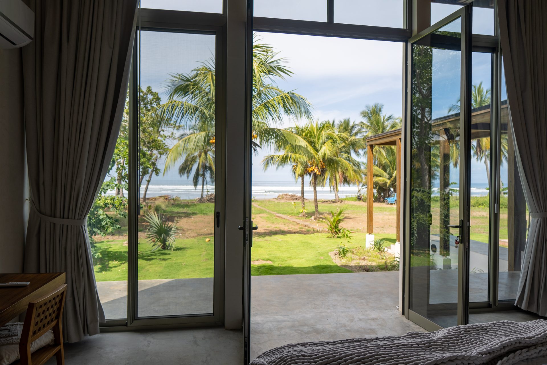Bedroom looking out to lawn and Pacific, beachfront family villa